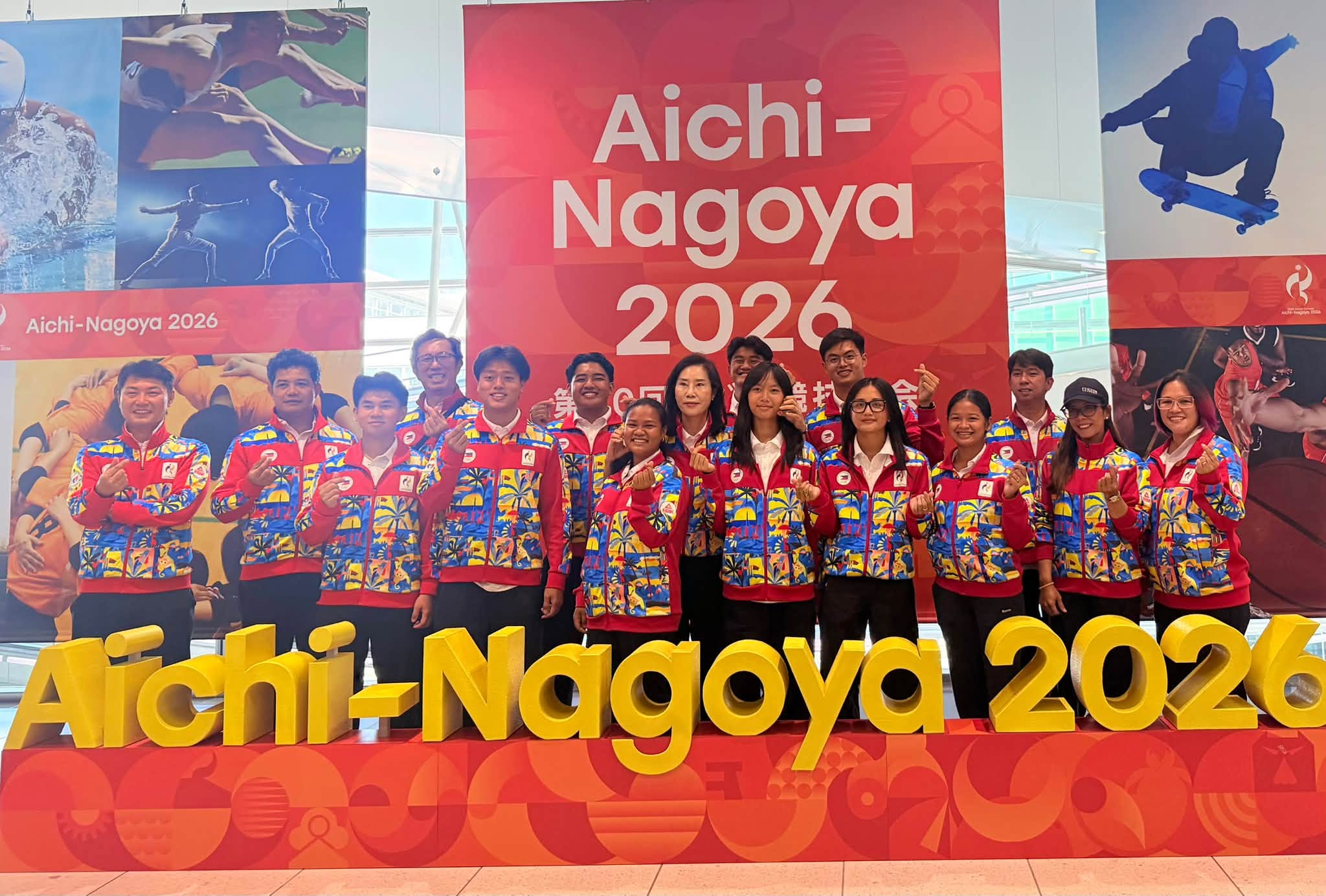 GG with travelers in front of the Aichi-Nagoya 2026 sign